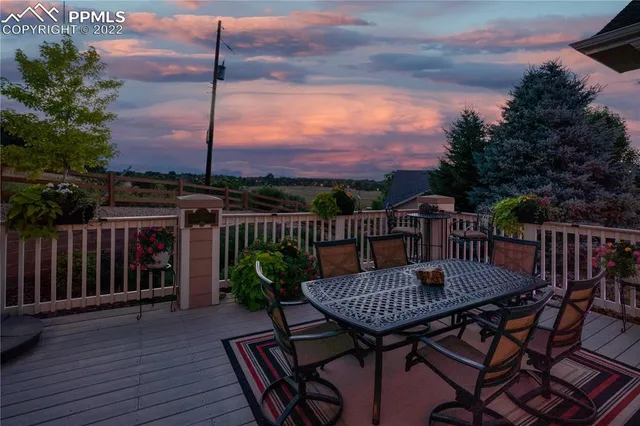 a view of a roof deck with table and chairs with wooden floor and fence