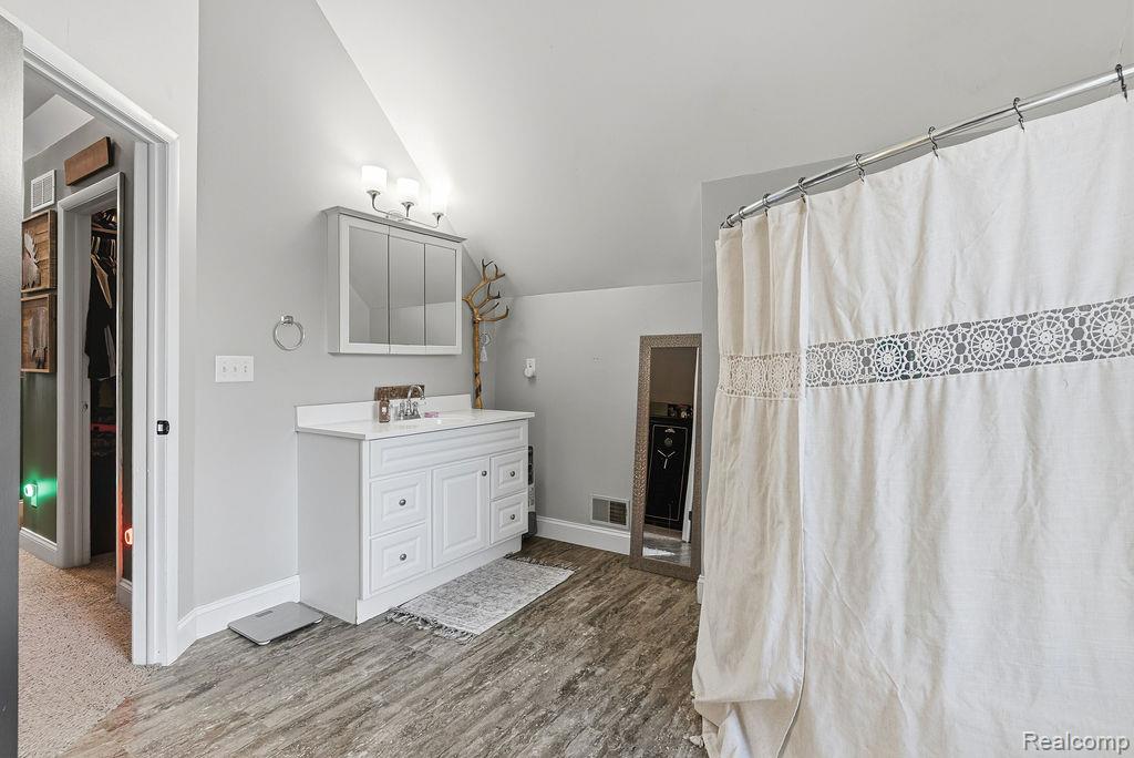 5216 South State Road Goodrich, MI 48438 - Photo 27 of 52 Bathroom with vaulted ceiling, vanity, a shower with shower curtain, a spacious closet, and light wood-style flooring