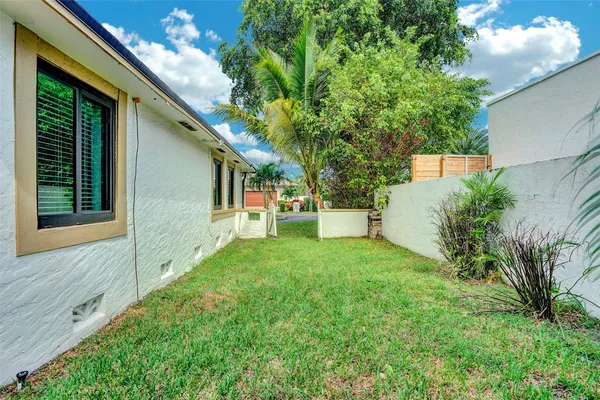 a view of house with a big yard potted plants and large tree