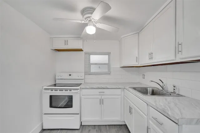 a kitchen with white cabinets and sink