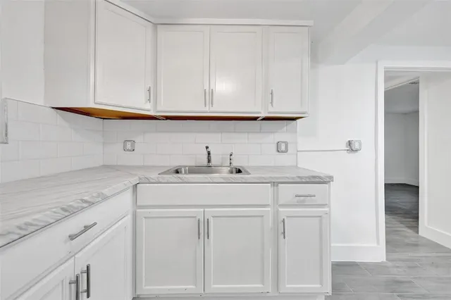 a kitchen with white cabinets and sink