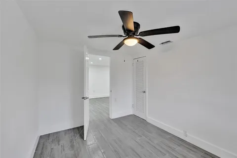 an empty room with wooden floor cabinet and ceiling fan