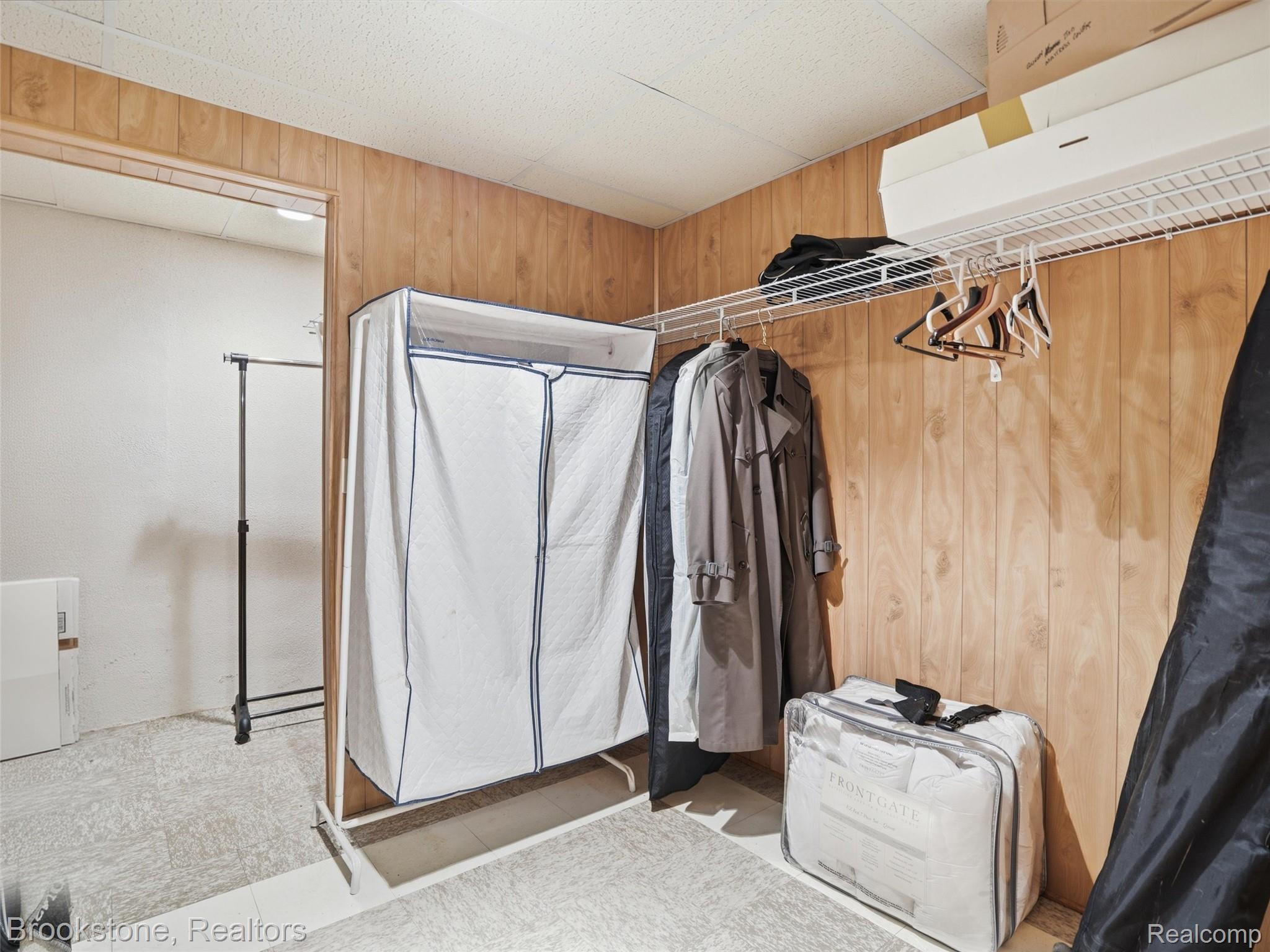 9523 Quail Ridge Run Brighton, MI 48114 - Photo 42 of 50 Utility room featuring wood-panel walls, white wire shelving, and light-colored flooring
