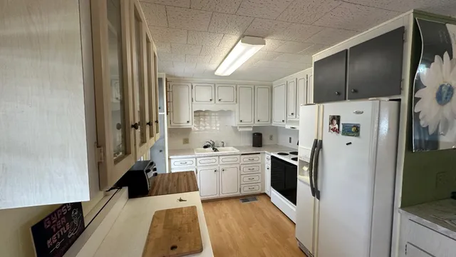 a large kitchen with a refrigerator a sink a stove and cabinets