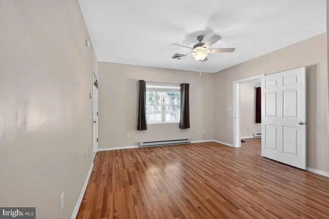 a view of an empty room with wooden floor and a window