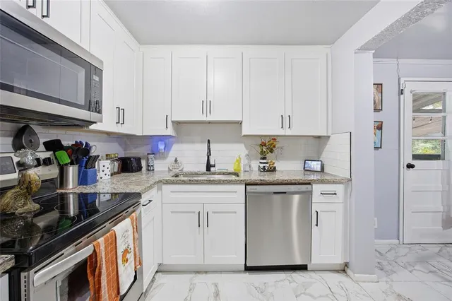 a kitchen with stainless steel appliances granite countertop a sink stove and cabinets