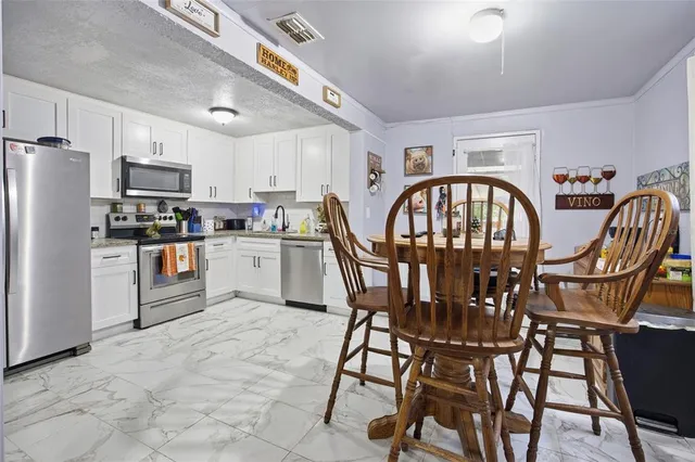 a kitchen with stainless steel appliances granite countertop a table chairs a refrigerator a stove a dining table and chairs