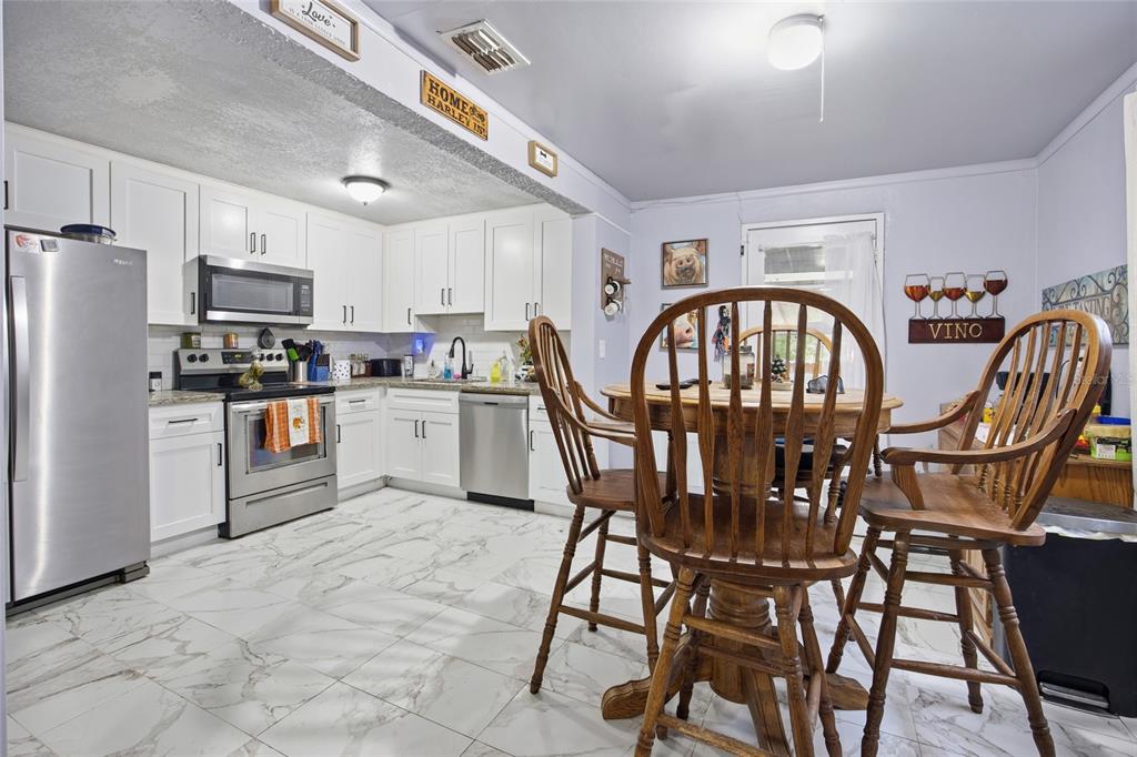 5403 East Tangelo Lane Inverness, FL 34453 - Photo 10 of 32 a kitchen with stainless steel appliances granite countertop a table chairs a refrigerator a stove a dining table and chairs