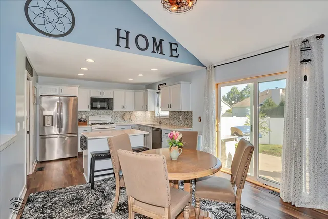 a view of a dining room with furniture a kitchen view and stainless steel appliances