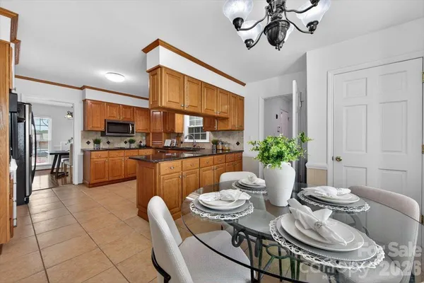 a kitchen with stainless steel appliances kitchen island granite countertop a sink a stove a dining table and chairs with wooden floor
