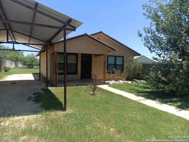 a backyard of a house with table and chairs under an umbrella