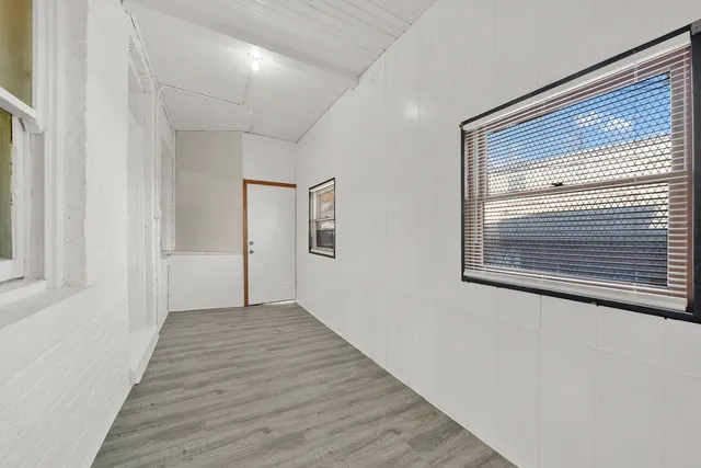 a view of a hallway with wooden floor and a window