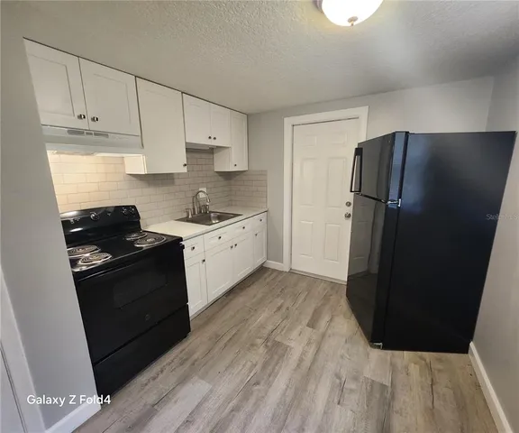 a kitchen with granite countertop white cabinets and refrigerator