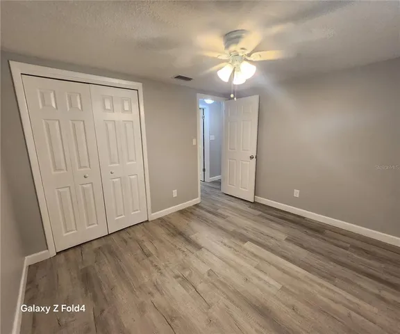 an empty room with wooden floor and chandelier fan