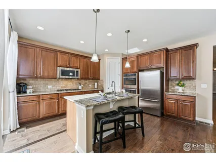 a kitchen with kitchen island granite countertop wooden cabinets and refrigerator