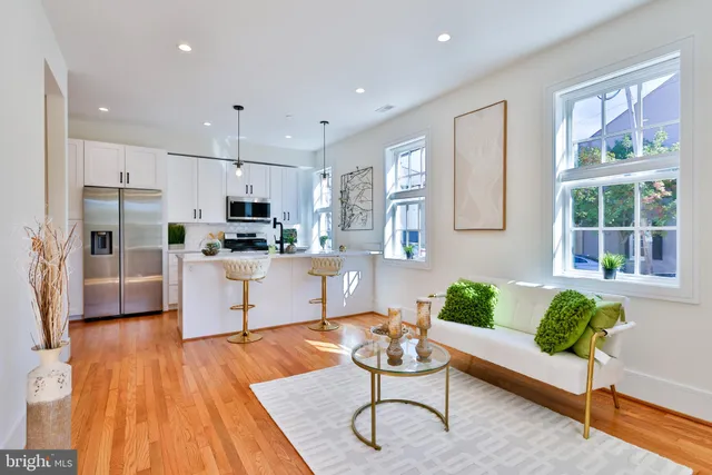 a kitchen with stainless steel appliances a refrigerator a sink dishwasher a stove and white cabinets with wooden floor