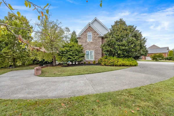 a view of a house with a yard and large trees