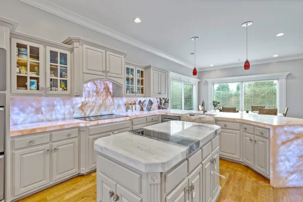 a large white kitchen with granite countertop a sink and white cabinets
