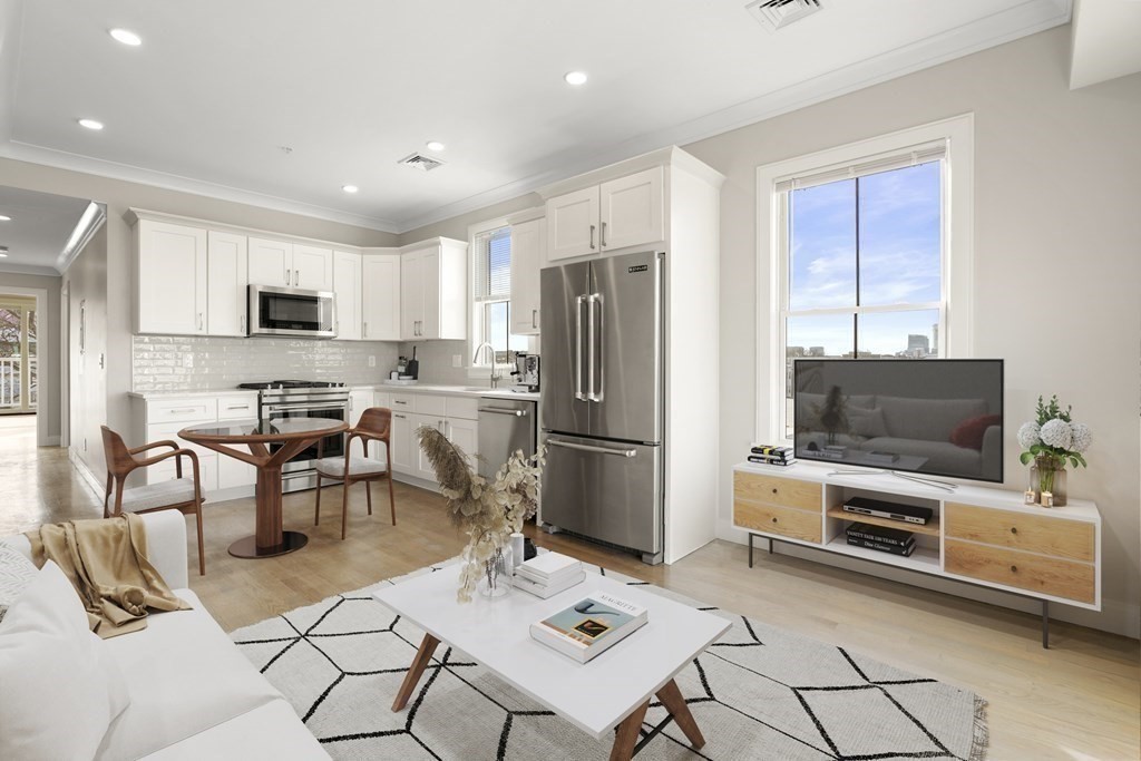 134 Chelsea Street, Unit 1 Boston, MA 02128 - Photo 2 of 13 a kitchen with stainless steel appliances a stove a refrigerator a sink a microwave and a dining table with wooden floor