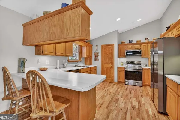 a kitchen with granite countertop a stove a sink a refrigerator and a dining table with wooden floor
