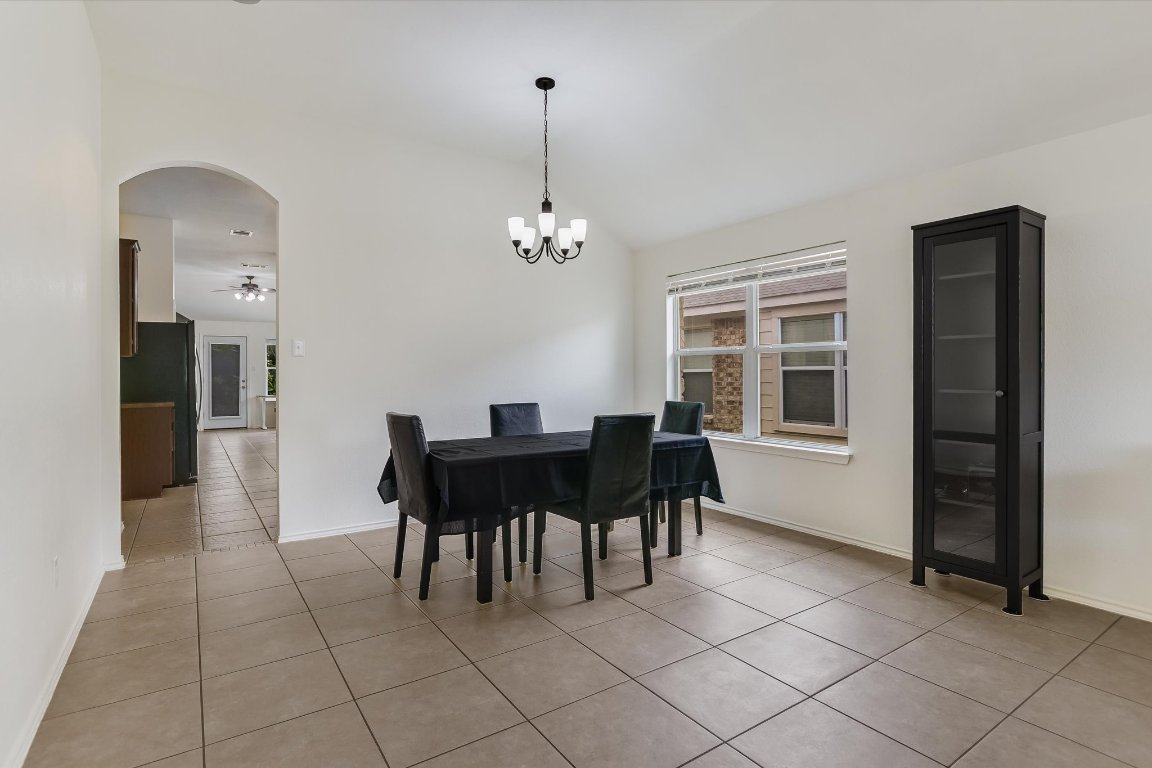 1901 Rachel Lane Round Rock, TX 78664 - Photo 14 of 35 Dining area with ceiling fan with notable chandelier, light tile patterned floors, arched walkways, baseboards, and lofted ceiling