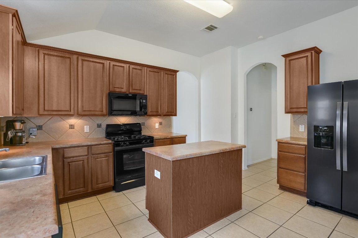1901 Rachel Lane Round Rock, TX 78664 - Photo 18 of 35 Kitchen featuring a sink, arched walkways, visible vents, black appliances, and light tile patterned floors