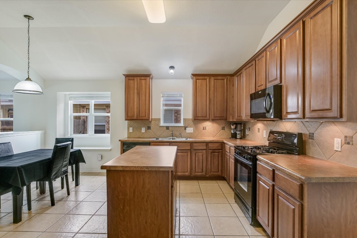 1901 Rachel Lane Round Rock, TX 78664 - Photo 20 of 35 Kitchen featuring decorative backsplash, a healthy amount of sunlight, a sink, and black appliances