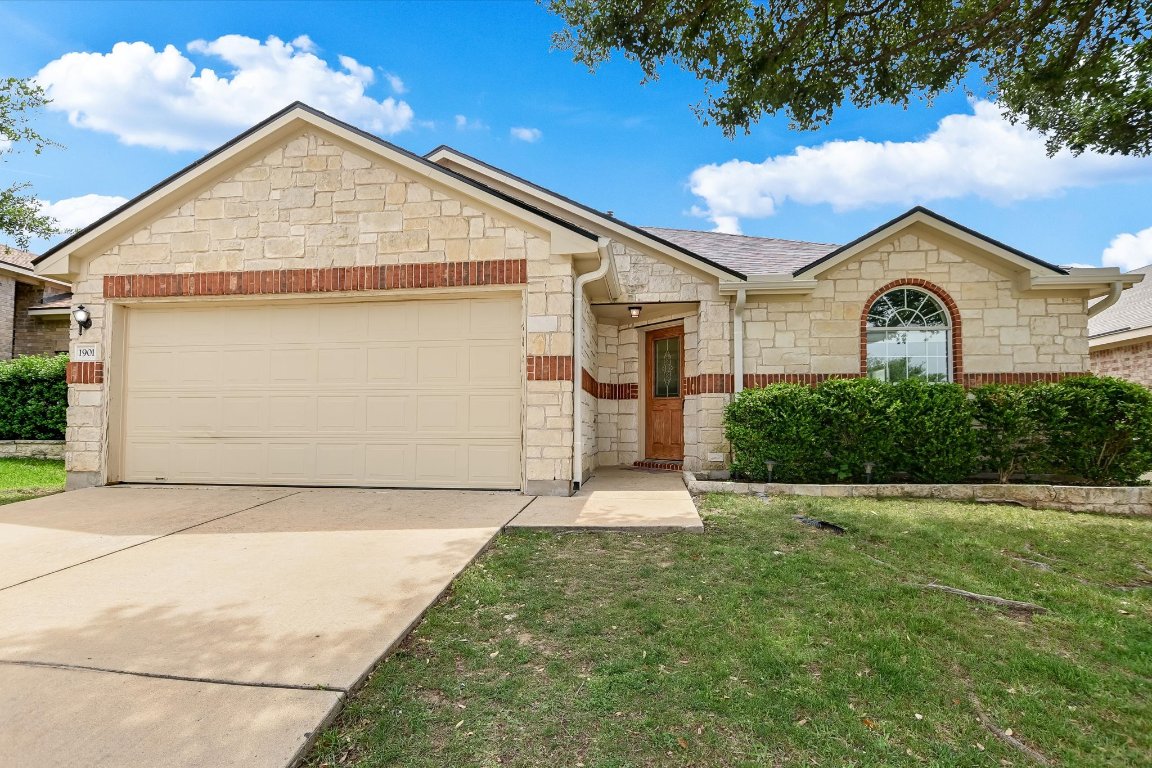 1901 Rachel Lane Round Rock, TX 78664 - Photo 3 of 35 Single story home with roof with shingles, stone siding, concrete driveway, an attached garage, and a front yard