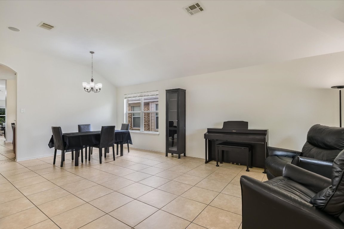 1901 Rachel Lane Round Rock, TX 78664 - Photo 7 of 35 Living area with vaulted ceiling, visible vents, light tile patterned floors, arched walkways, and a chandelier