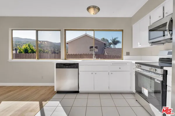 a kitchen with granite countertop white cabinets stainless steel appliances and a counter space