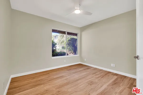 an empty room with wooden floor cabinet and windows