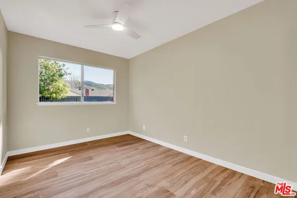 an empty room with wooden floor and mirror