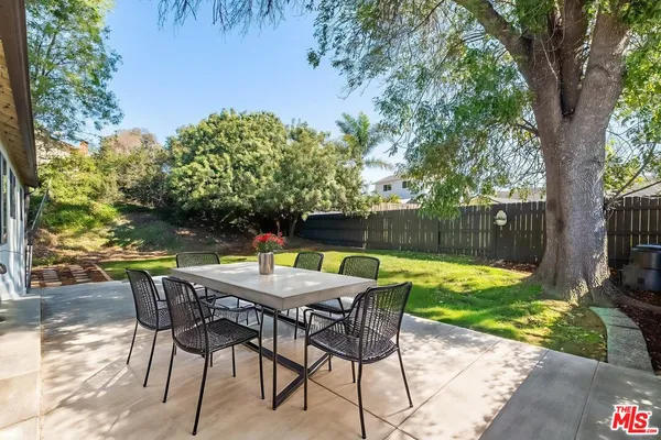 a view of a backyard with a large tree and wooden fence