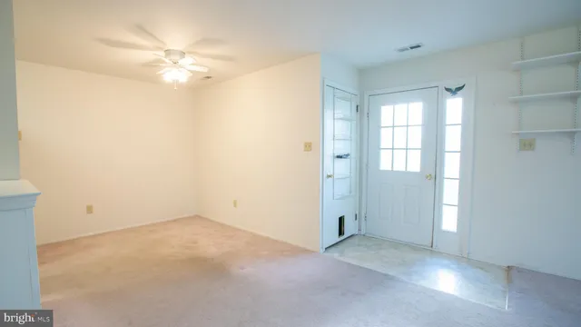 an empty room with windows and chandelier fan