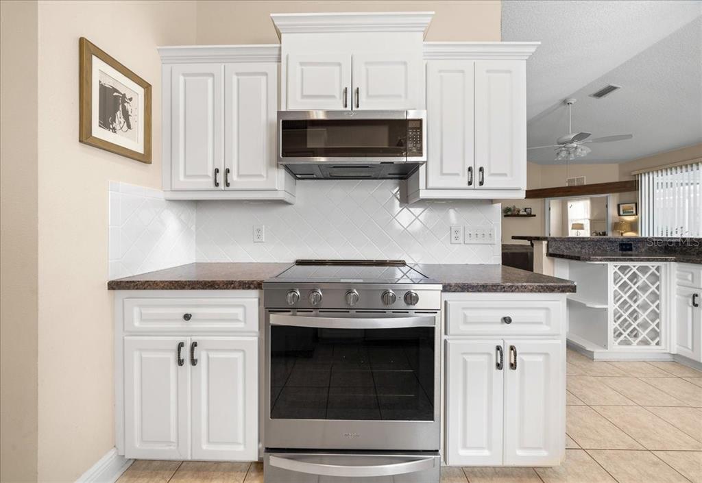 2197 Northwest 55th Avenue Road Ocala, FL 34482 - Photo 49 of 66 a kitchen with stainless steel appliances granite countertop white cabinets a sink a stove and a microwave