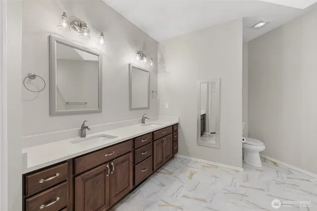 a spacious bathroom with a double vanity sink a toilet and a mirror