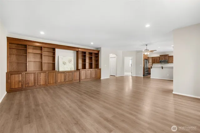 a view of an empty room with wooden floor and a kitchen