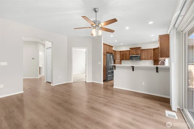 a view of a kitchen with wooden floor a sink a refrigerator and a window