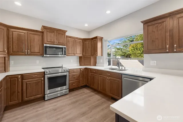 a kitchen with kitchen island granite countertop wooden cabinets a stove a sink and dishwasher with wooden floor