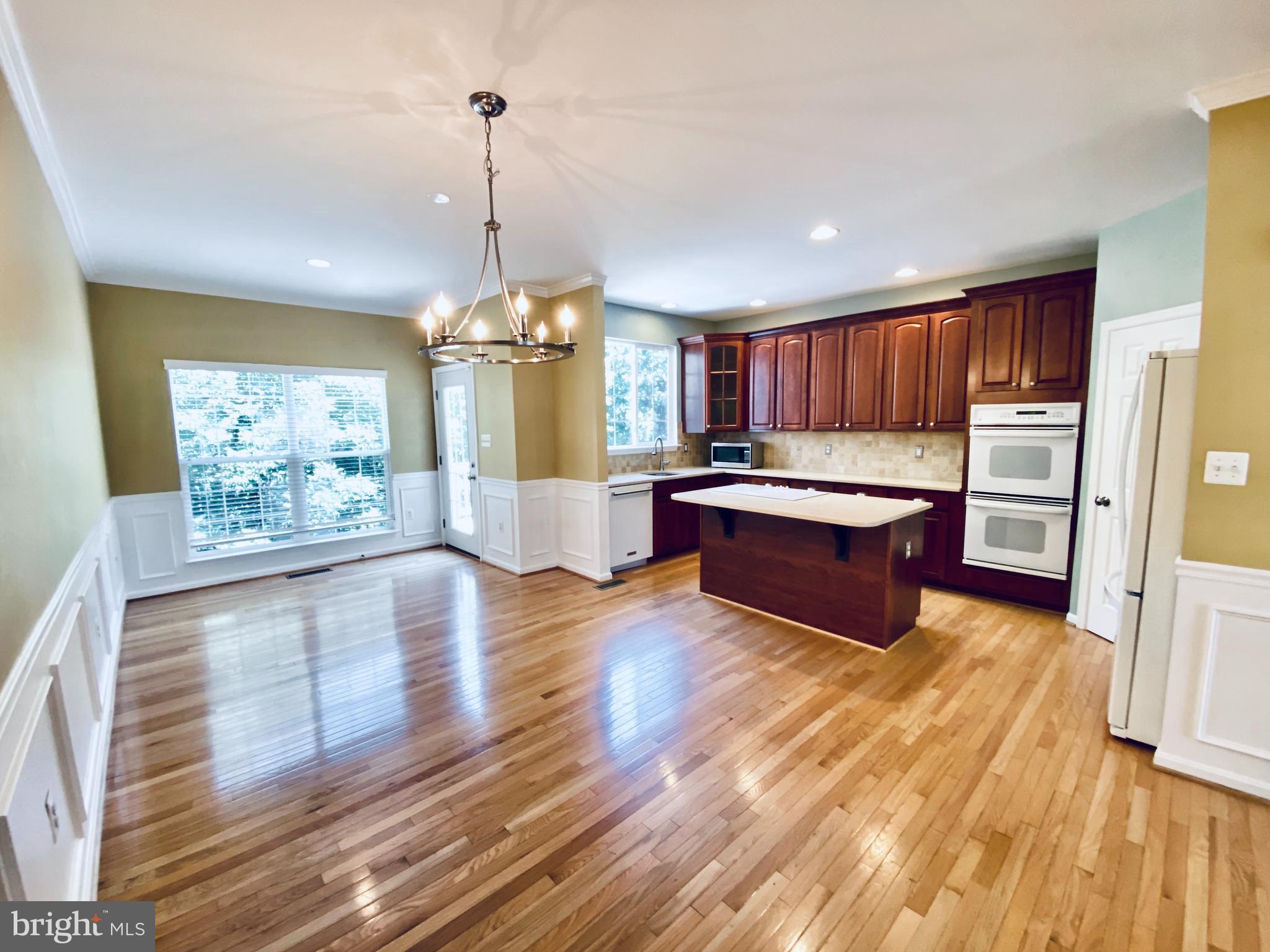 8381 Jovin Circle Springfield, VA 22153 - Photo 6 of 16 a open kitchen with stainless steel appliances granite countertop a refrigerator a sink dishwasher a stove and white countertops with wooden floor
