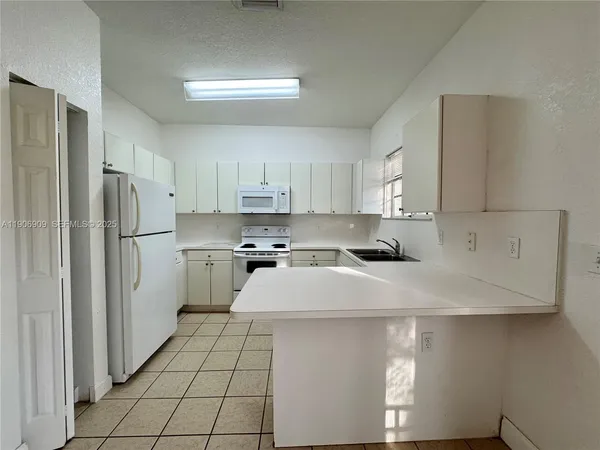 a kitchen with white cabinets and white appliances