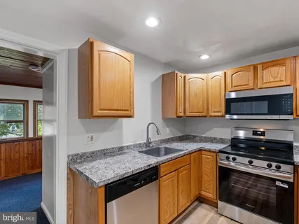 a kitchen with granite countertop a sink cabinets and stainless steel appliances