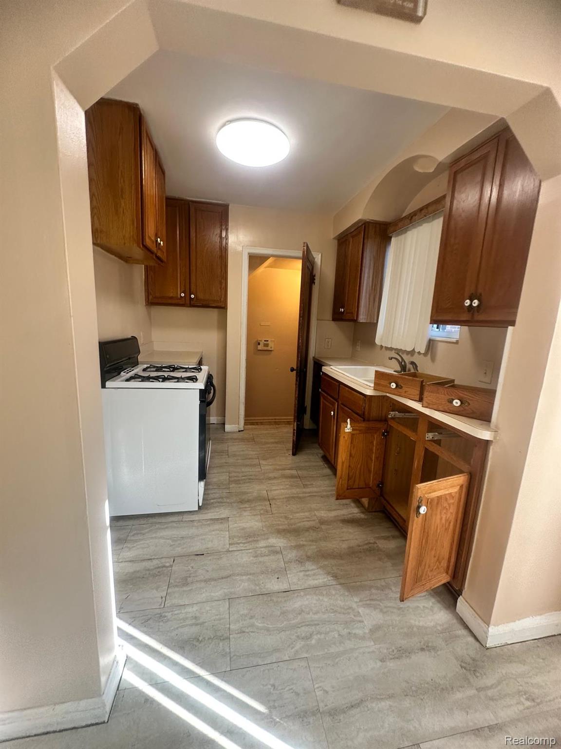 13644 Castleton Street Detroit, MI 48227 - Photo 5 of 18 Kitchen featuring wood cabinetry, a white gas range, and light-toned tile flooring