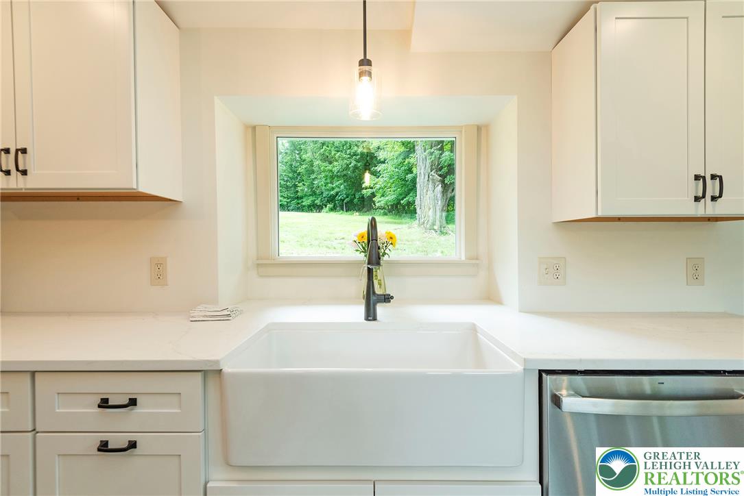 72 Allegheny Road Mount Bethel, PA 18343 - Photo 13 of 72 A spacious farmhouse sink anchors this kitchen, offering picturesque views of the lush green outdoors.