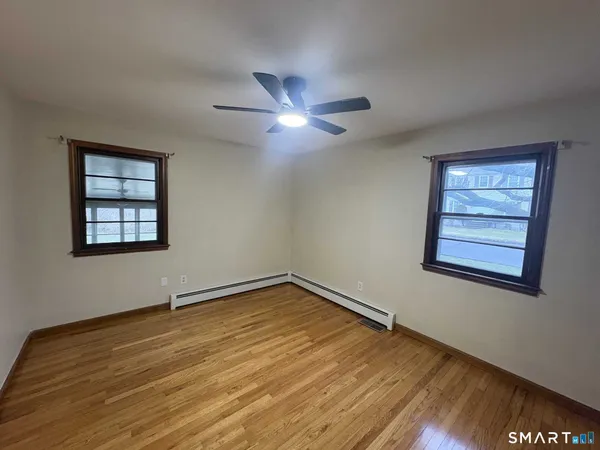a view of empty room with wooden floor and fan