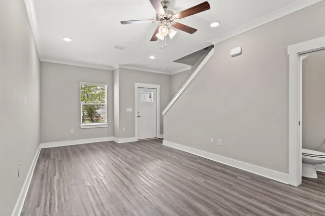 an empty room with wooden floor chandelier fan and windows