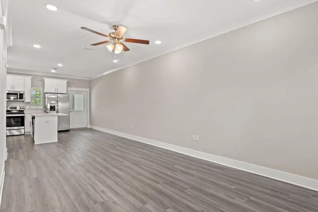 a view of a kitchen with a sink a ceiling fan and wooden floor