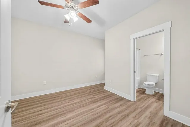 an empty room with wooden floor ceiling fan and windows