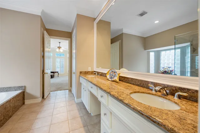 a spacious bathroom with a granite countertop double vanity sink a mirror and a bathtub