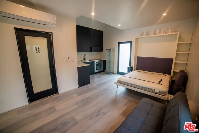 a living room with stainless steel appliances furniture and a flat screen tv